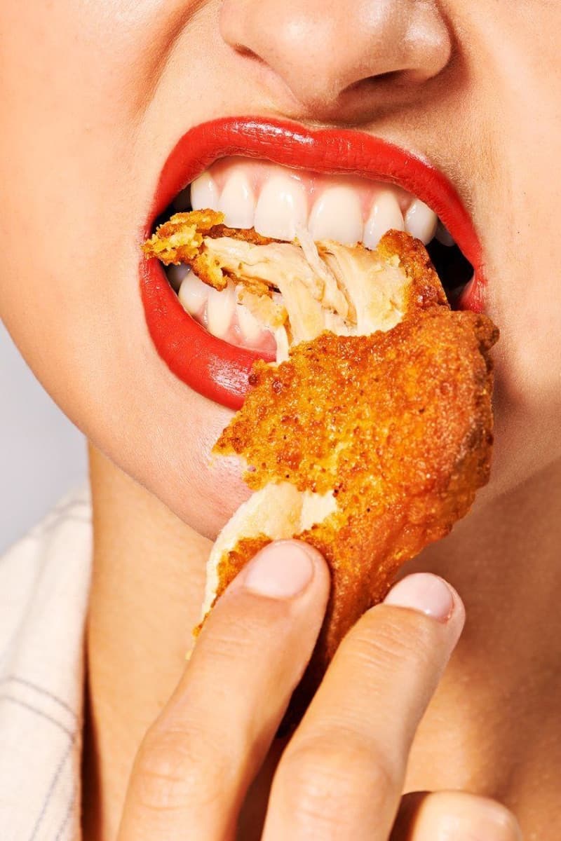 Boca mordendo um pedaço de frango frito crocante